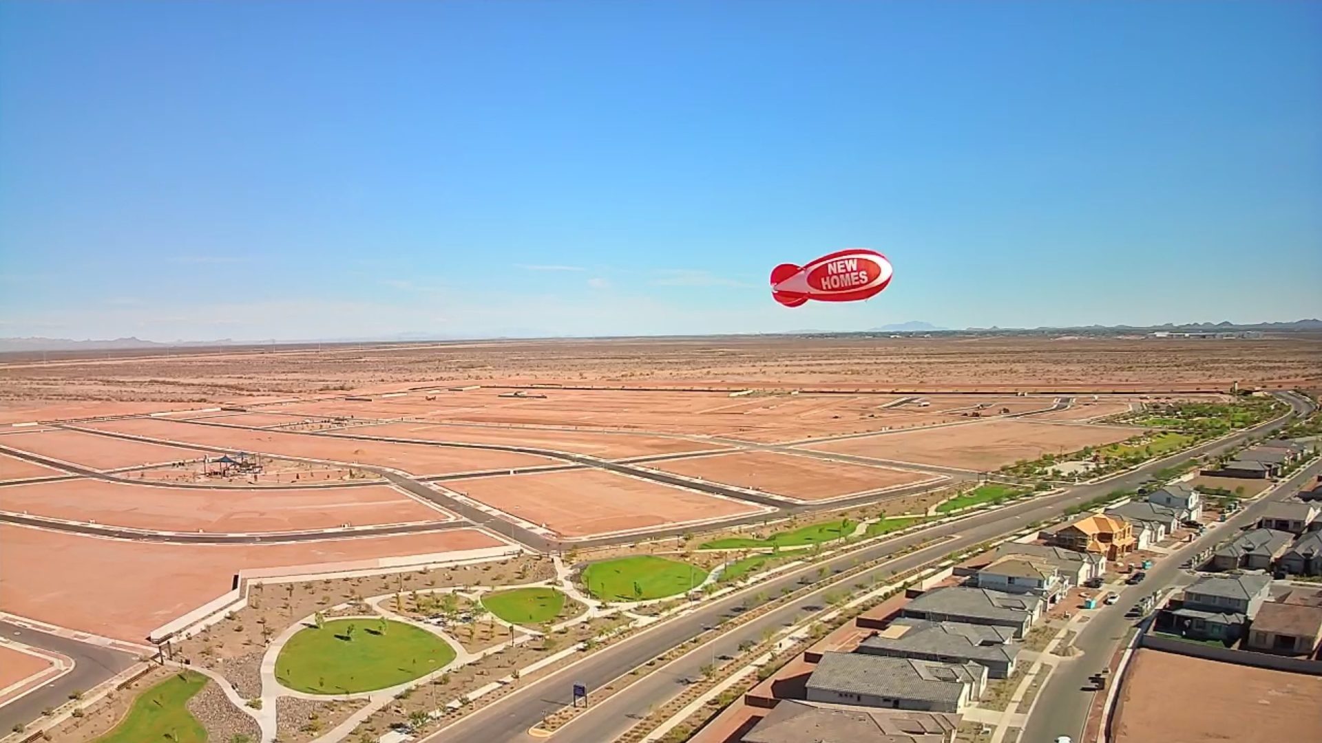 Red advertising blimp flying 120 feet above a new home development